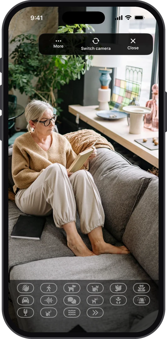 AiCam camera watching an older woman reading on the sofa